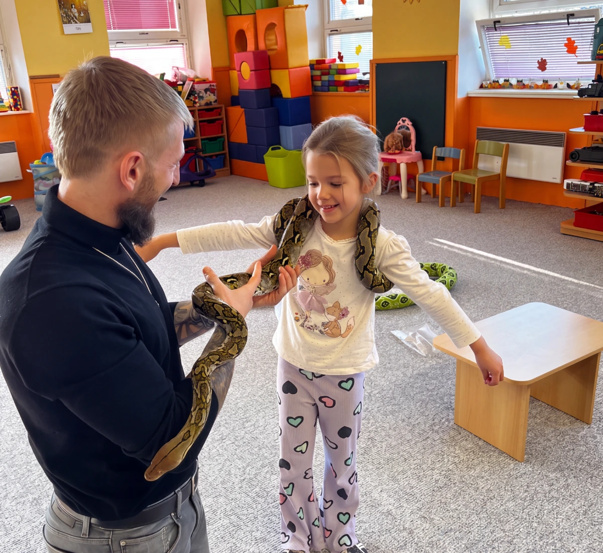 Zdeněk s hadem před dětmi na koberci